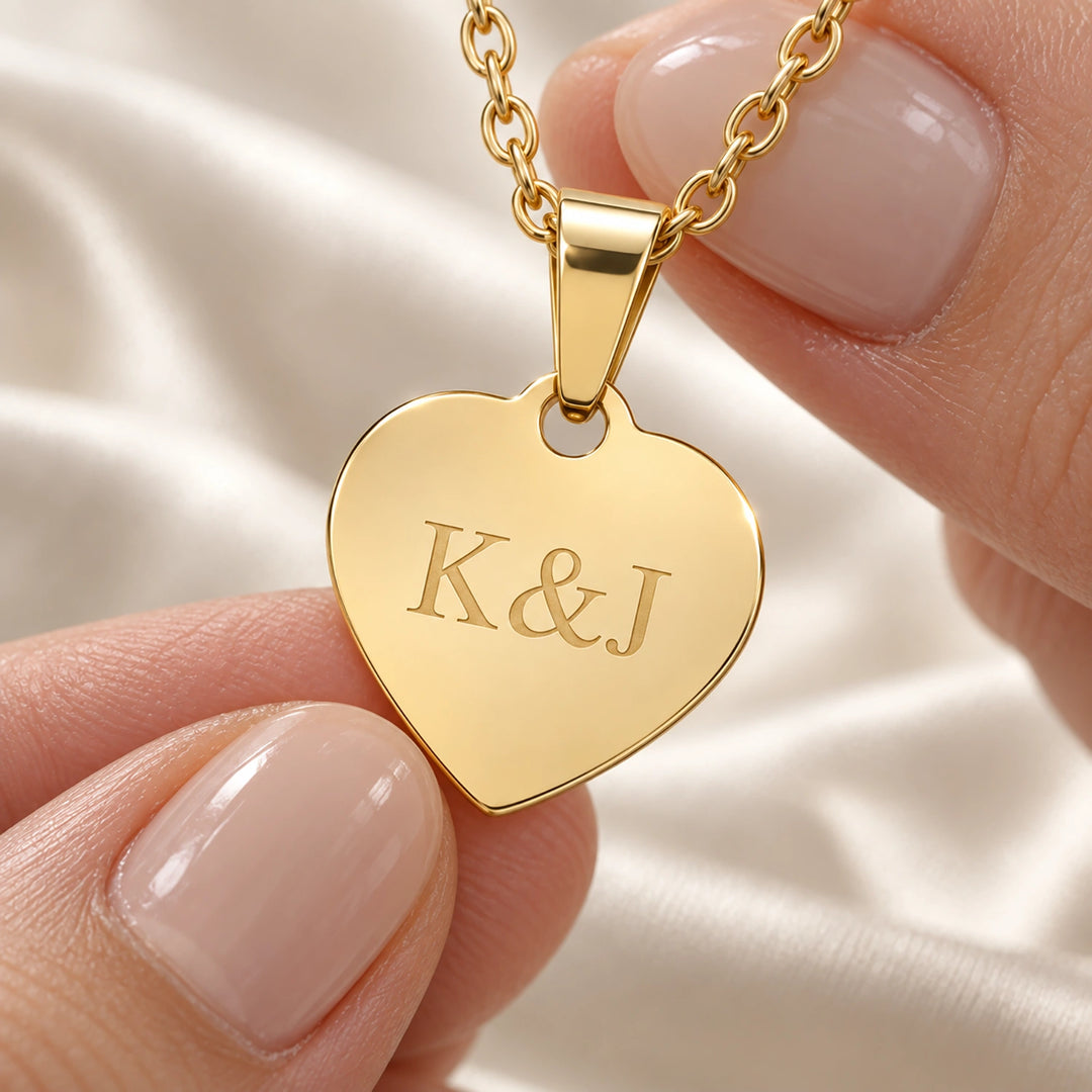 Fingers holding the gold Love heart pendant engraved with initials