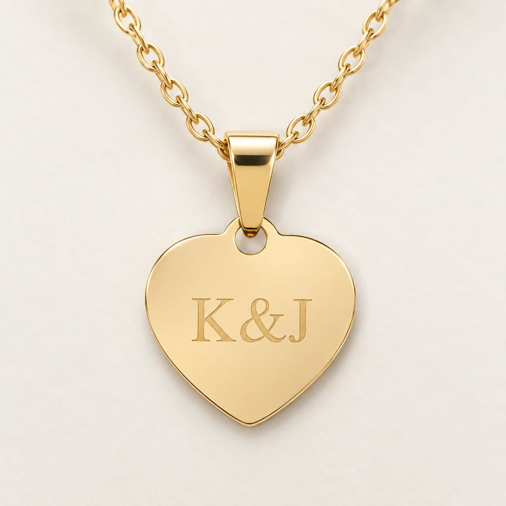 Close-up of the gold Love heart pendant with personalized engraving on a cream background