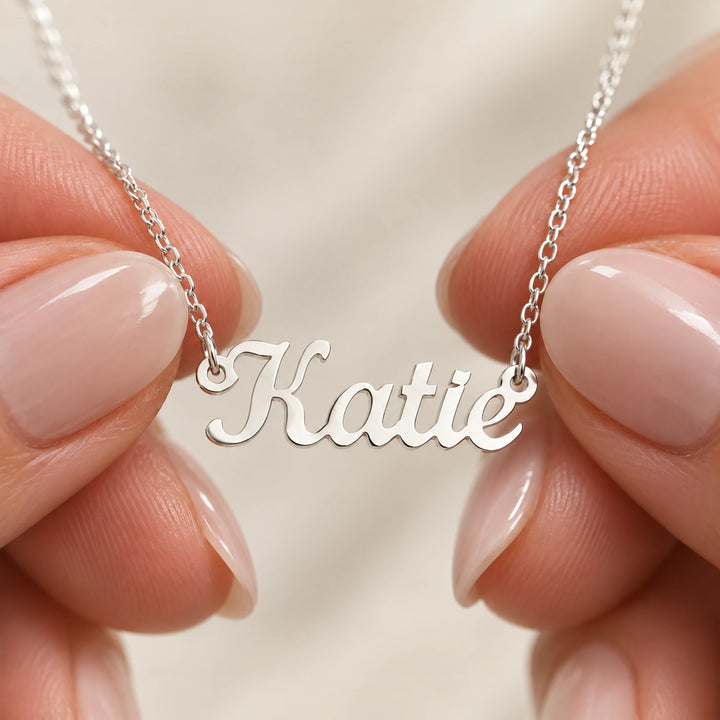Fingertips holding the silver Name necklace by its chain