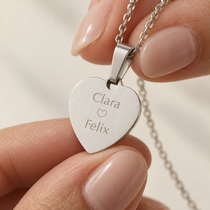 Fingers holding the silver Love heart pendant engraved with names