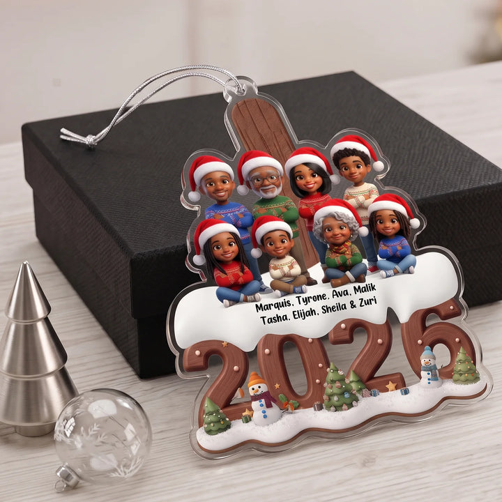 Ornament with nine family members as cartoon figures with Santa hats and their names above the year 2026 in front of a black gift box