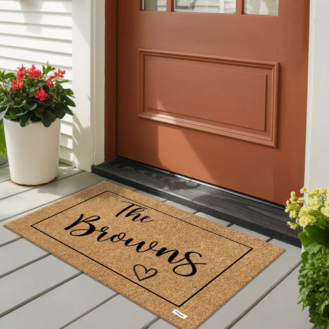 Family name doormat on a porch in front of a red door