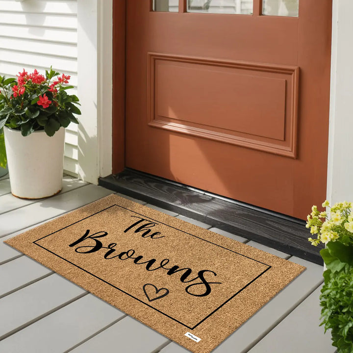 Family name doormat on a porch in front of a red door