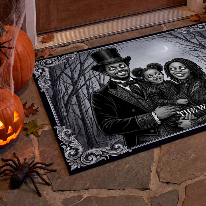 Close-up of the Halloween family photo doormat beside jack-o'-lanterns and a spider