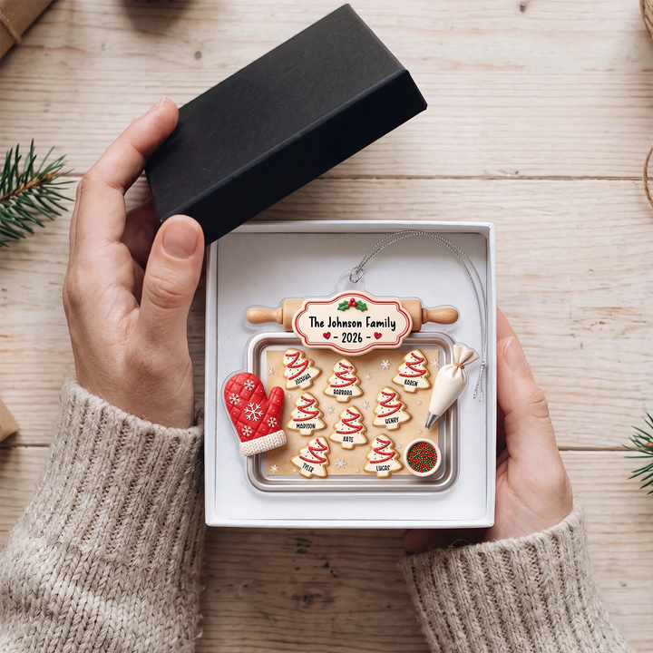 Hands open a gift box with the cookie tray family ornament inside