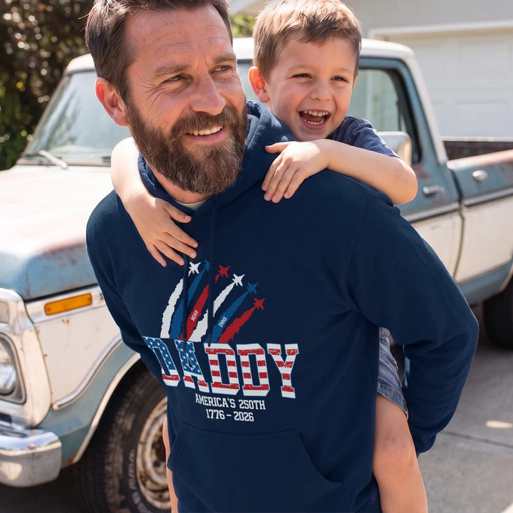 Laughing dad carries his son piggyback in a navy DADDY American Legend hoodie