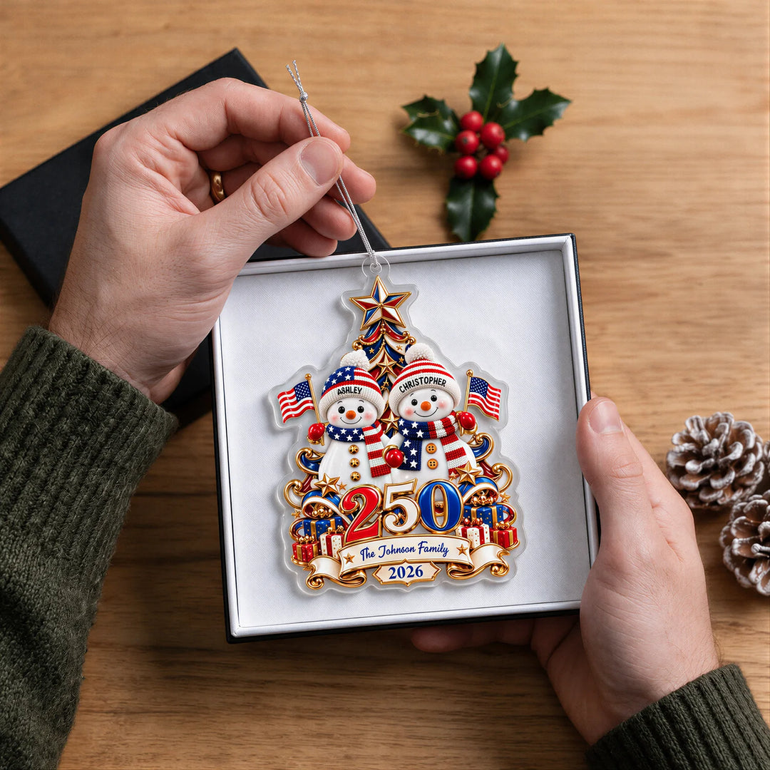 Hands holding the Snowman 250 Years ornament with two snowmen and The Johnson Family in a gift box