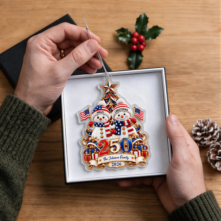 Hands holding the Snowman 250 Years ornament with two snowmen and The Johnson Family in a gift box