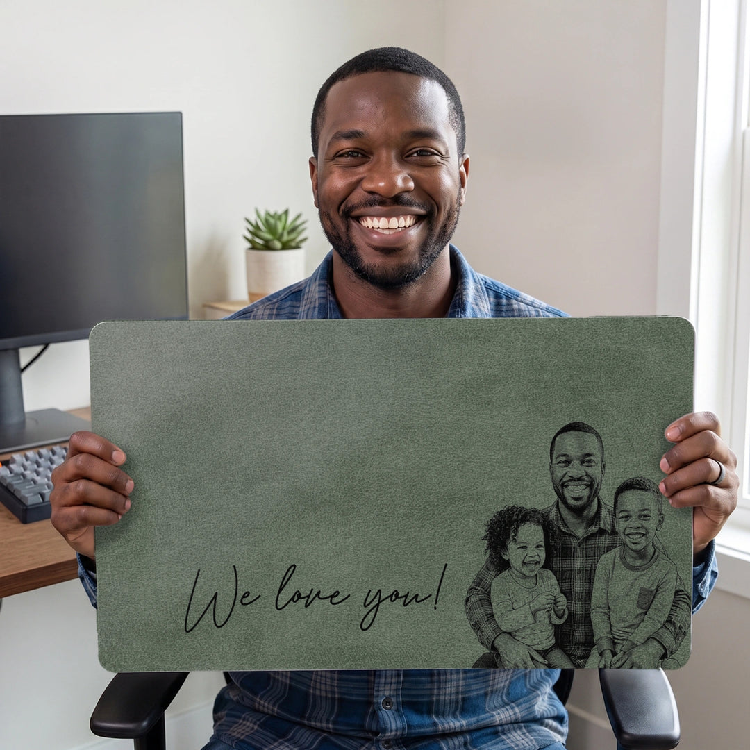 Smiling dad holding the green We love you desk mat with family line drawing