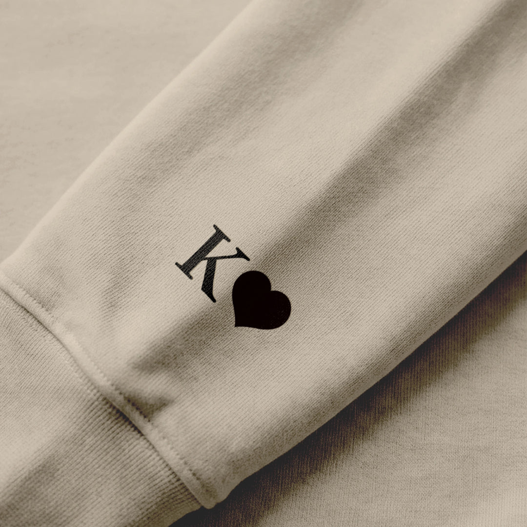 Close-up of the sleeve print with initial and heart on a sand hoodie