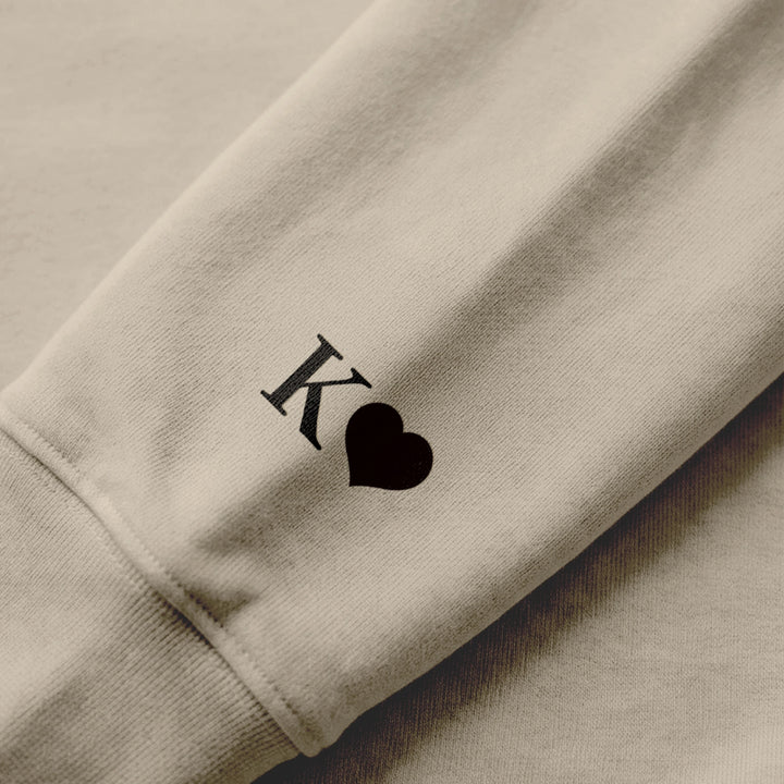 Close-up of the sleeve print with initial and heart on a sand hoodie