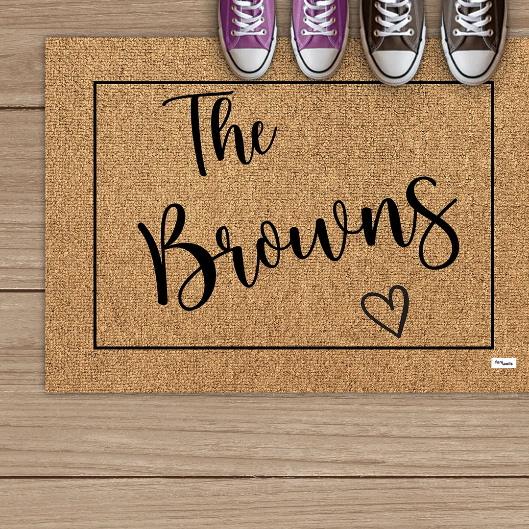 Brown family name doormat below a row of sneakers on wooden boards