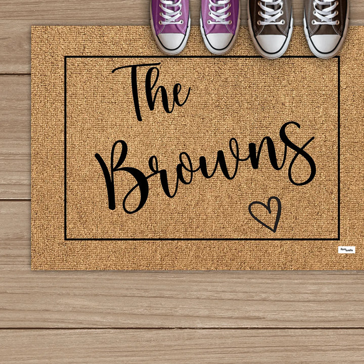 Brown family name doormat below a row of sneakers on wooden boards