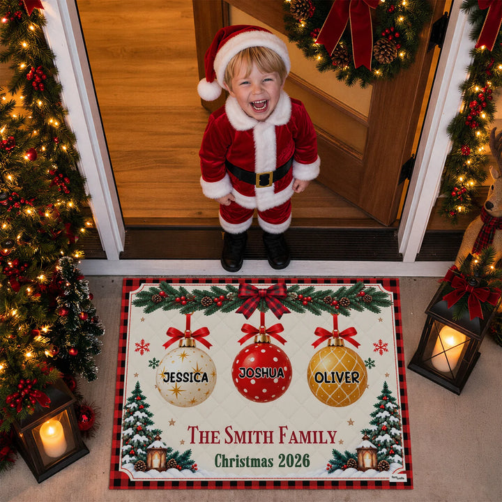 Laughing child in a Santa suit standing above the Christmas Family doormat
