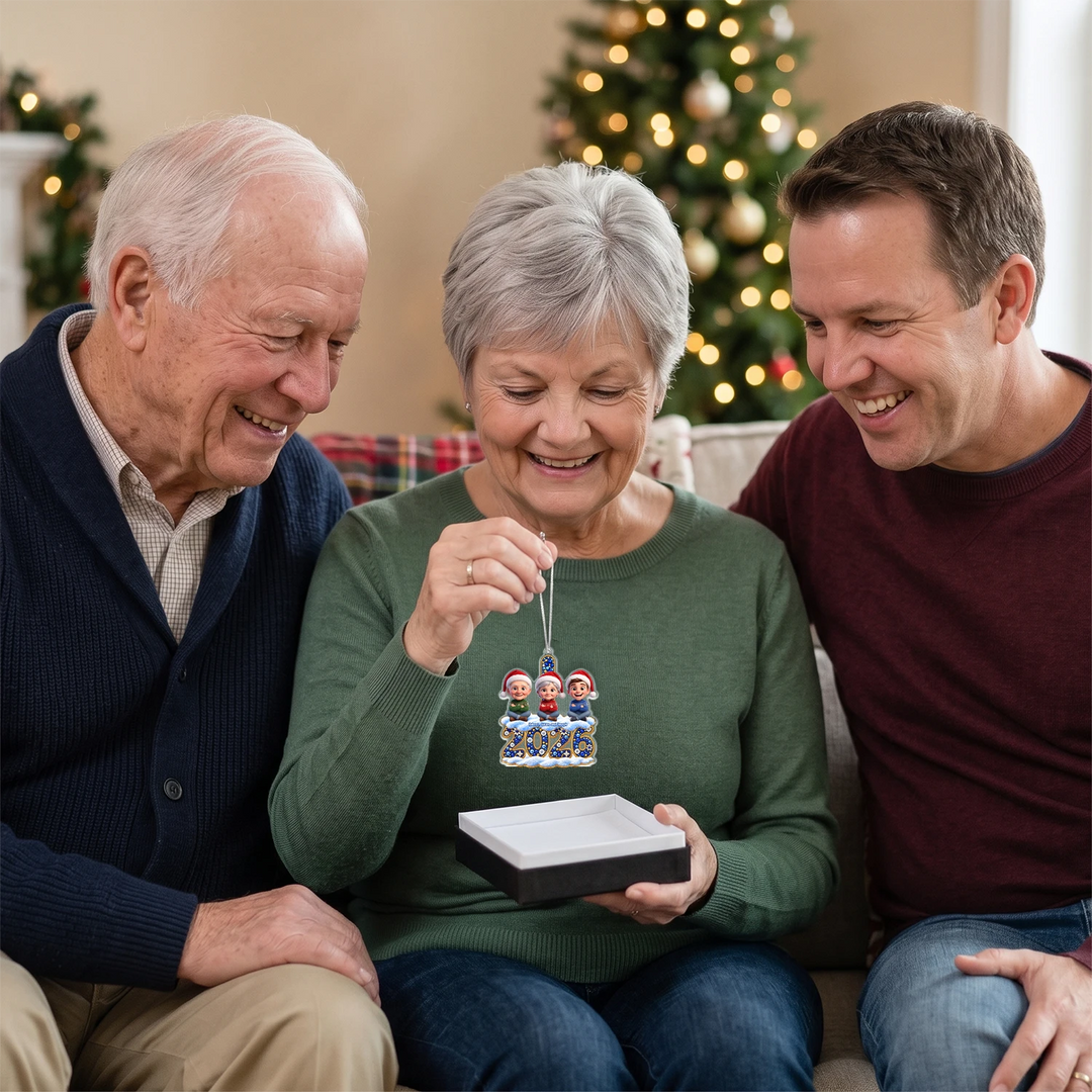 Grandparents and son smiling at the personalized 2026 family ornament from a gift box