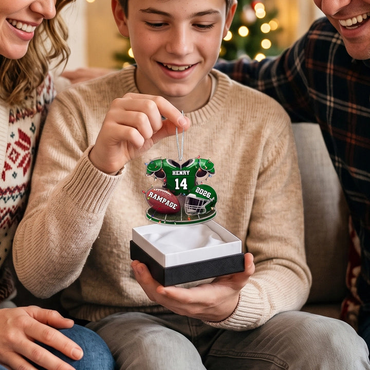Teen unwraps the green Football ornament with his family
